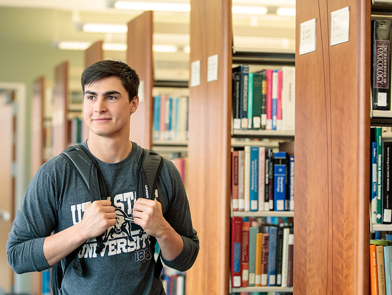 student walking through the library stacks